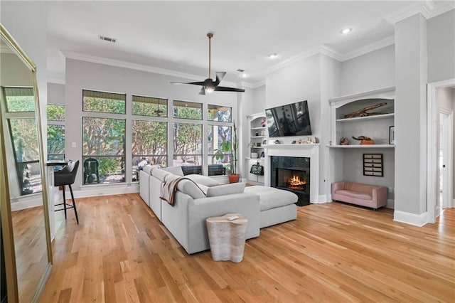 living room featuring ceiling fan, crown molding, and light hardwood / wood-style floors