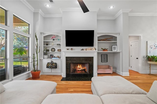 living room featuring a fireplace, a towering ceiling, hardwood / wood-style flooring, and ornamental molding