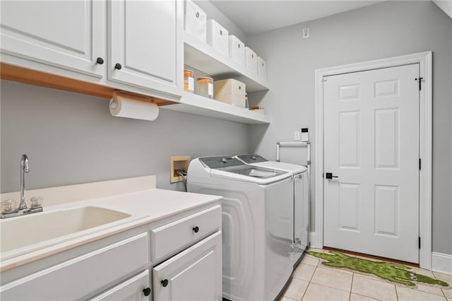 clothes washing area with cabinets, light tile patterned floors, sink, and washing machine and dryer