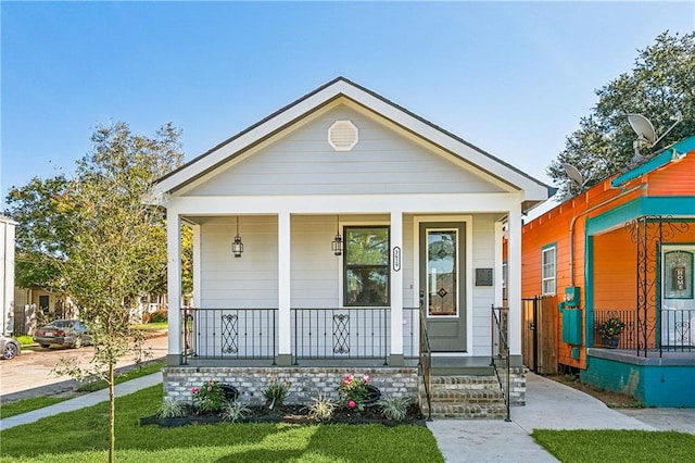 bungalow featuring a porch and a front lawn