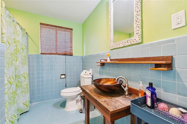 bathroom with toilet, tile walls, and sink