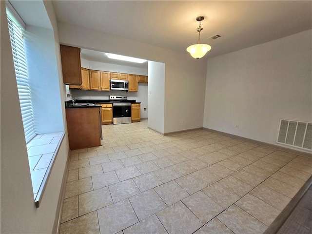 kitchen featuring appliances with stainless steel finishes, light tile patterned floors, hanging light fixtures, and sink