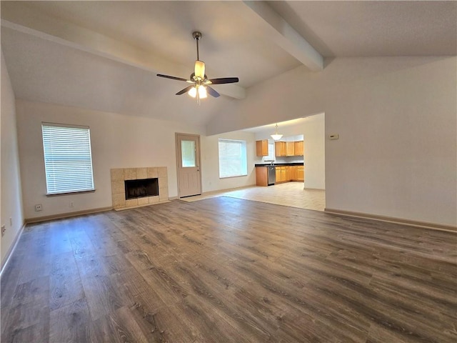 unfurnished living room featuring a fireplace, hardwood / wood-style floors, lofted ceiling with beams, and ceiling fan