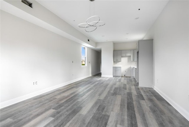 unfurnished living room featuring dark hardwood / wood-style flooring and a notable chandelier