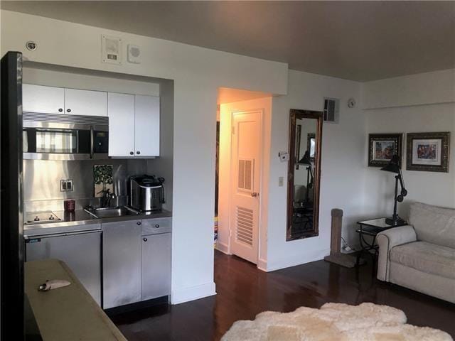 kitchen featuring white cabinetry, backsplash, dark hardwood / wood-style flooring, stainless steel counters, and sink