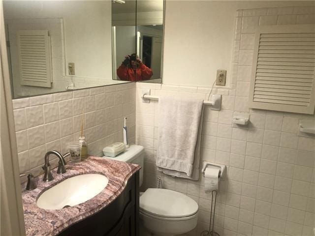 bathroom featuring tile walls, toilet, and vanity