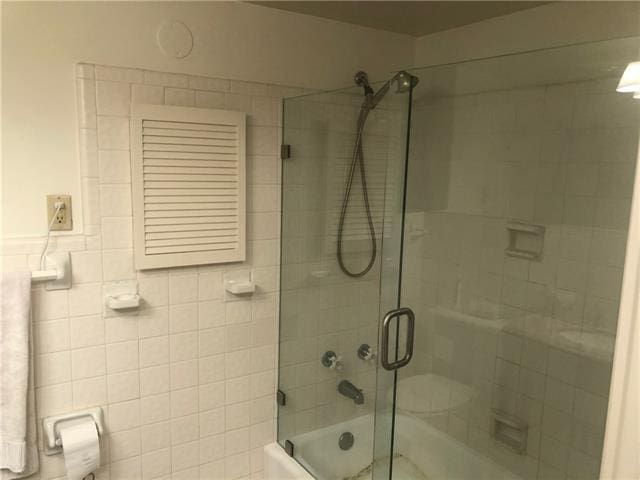 bathroom featuring tile walls and enclosed tub / shower combo