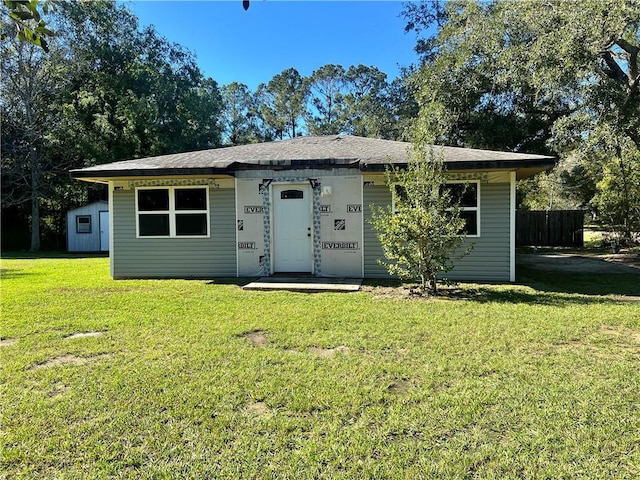 ranch-style house featuring a front yard and a shed