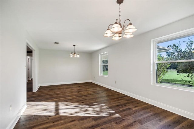 unfurnished dining area with dark hardwood / wood-style flooring, plenty of natural light, and an inviting chandelier