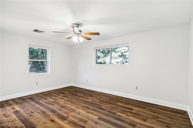 spare room with a wealth of natural light, ceiling fan, and dark hardwood / wood-style floors