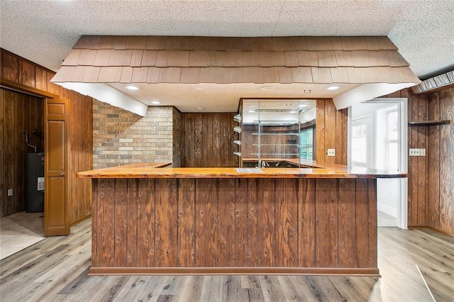 bar with wooden walls, light hardwood / wood-style flooring, and water heater