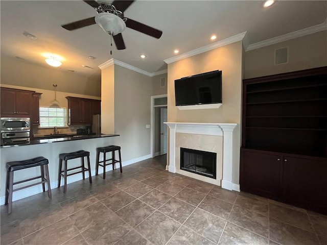 tiled living room featuring a premium fireplace, crown molding, ceiling fan, and sink