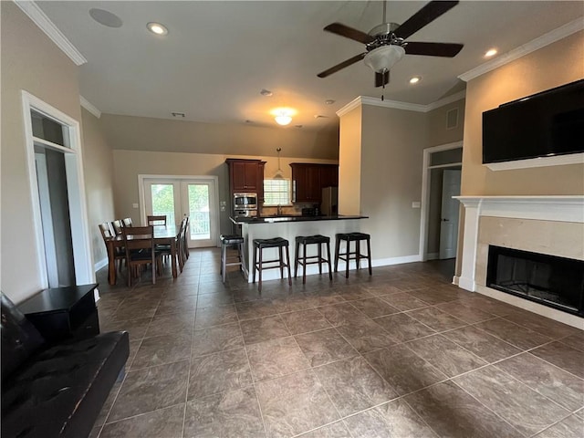 kitchen with a kitchen bar, ceiling fan, stainless steel appliances, and ornamental molding