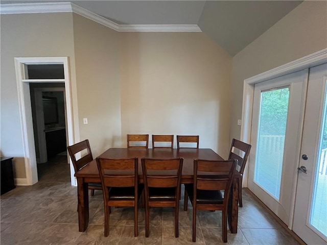 dining space featuring dark tile patterned flooring, lofted ceiling, and crown molding