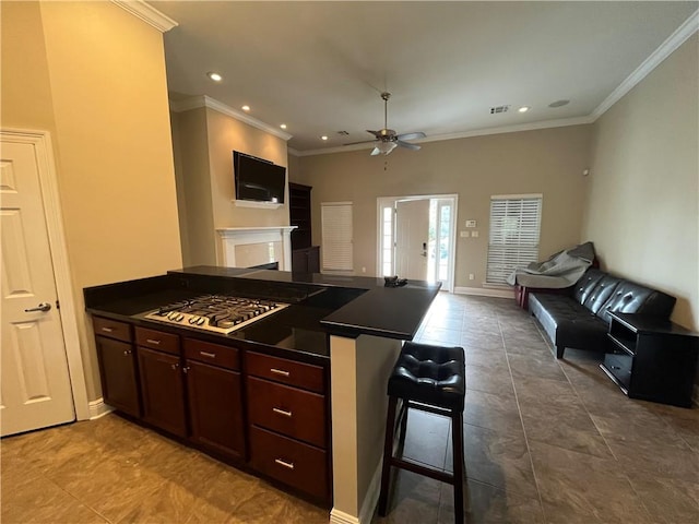 kitchen with ceiling fan, a kitchen bar, ornamental molding, and kitchen peninsula