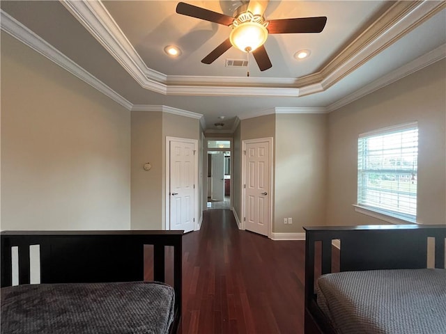 bedroom featuring dark wood-type flooring, ceiling fan, crown molding, and a tray ceiling