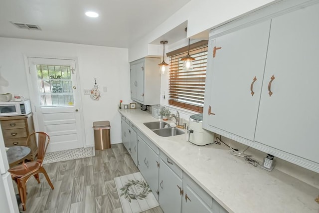 kitchen featuring pendant lighting, light wood-type flooring, and sink