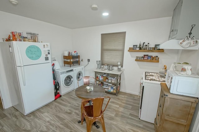 laundry area with washing machine and clothes dryer and light hardwood / wood-style flooring