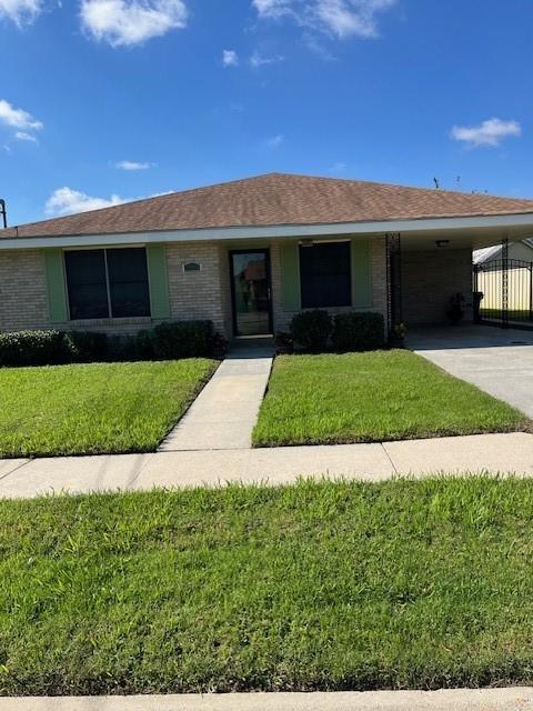 single story home featuring a front lawn and a carport