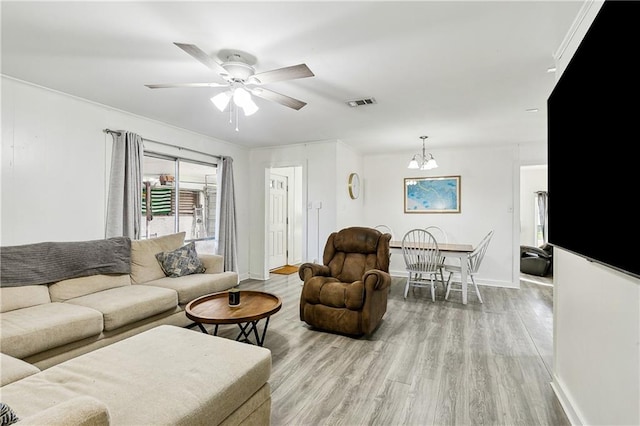 living room with ceiling fan with notable chandelier, crown molding, and light hardwood / wood-style flooring