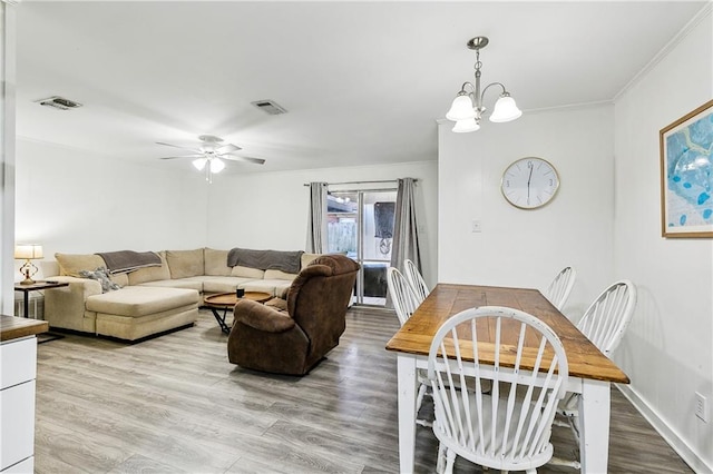 living room with ceiling fan with notable chandelier, wood-type flooring, and crown molding