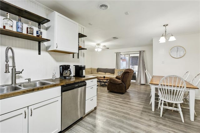 kitchen with stainless steel dishwasher, sink, decorative light fixtures, light hardwood / wood-style flooring, and white cabinetry