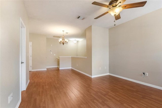 unfurnished room featuring ceiling fan with notable chandelier and hardwood / wood-style flooring