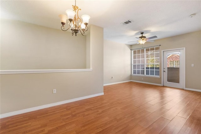 empty room with ceiling fan with notable chandelier and wood-type flooring