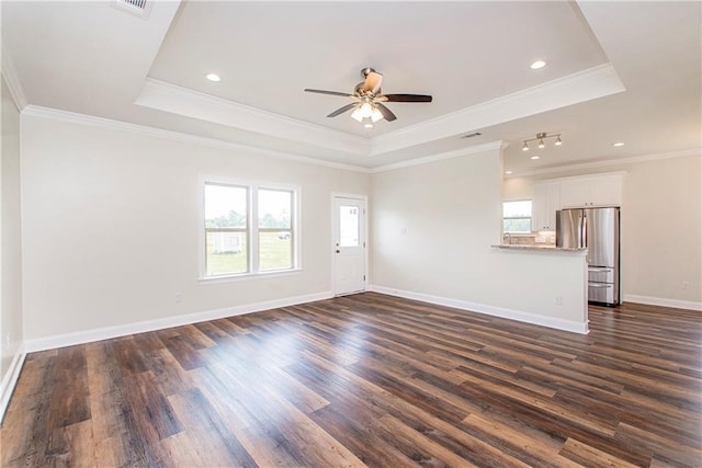 unfurnished living room with a tray ceiling, dark hardwood / wood-style floors, and ornamental molding