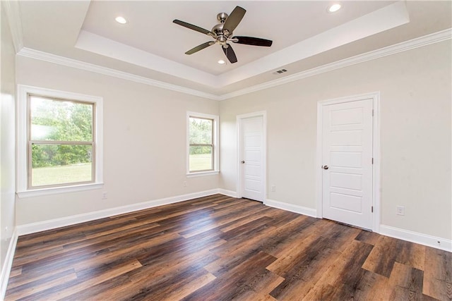 unfurnished bedroom featuring dark hardwood / wood-style flooring, a tray ceiling, and ceiling fan