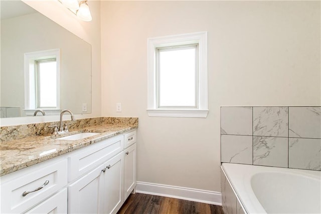 bathroom with hardwood / wood-style flooring, vanity, and a washtub