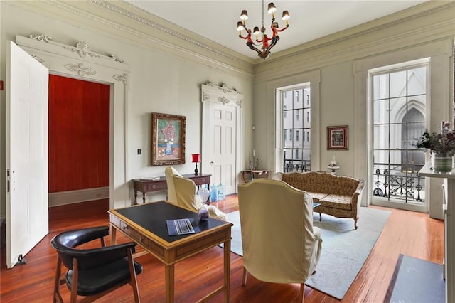 living area with crown molding, wood-type flooring, and a notable chandelier