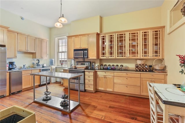 kitchen featuring appliances with stainless steel finishes, light brown cabinets, light hardwood / wood-style floors, and pendant lighting