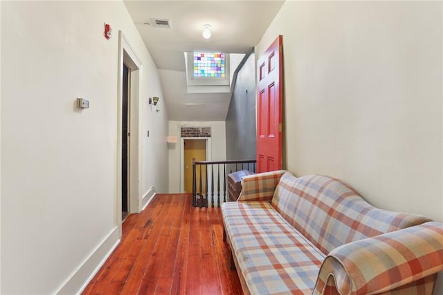 hallway with hardwood / wood-style floors and vaulted ceiling