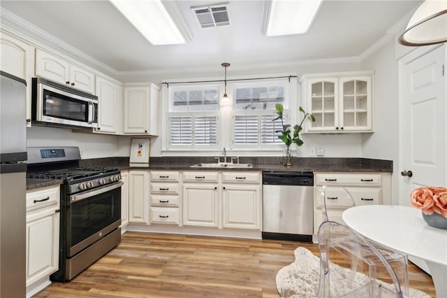 kitchen featuring crown molding, sink, light hardwood / wood-style flooring, appliances with stainless steel finishes, and decorative light fixtures