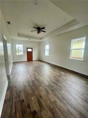 1833 Saint Ferdinand St, New Orleans, LA 70117 - unfurnished living room with a raised ceiling, dark wood-style flooring, baseboards, and ceiling fan