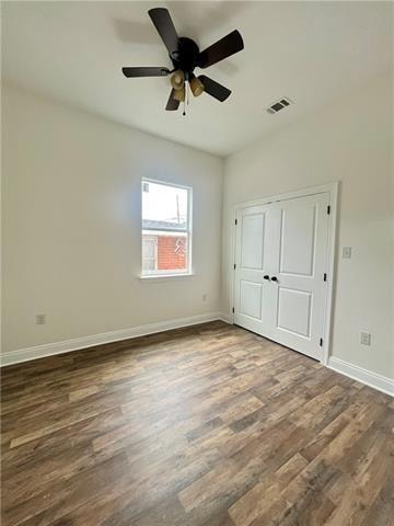 unfurnished bedroom featuring ceiling fan, dark wood-type flooring, and a closet