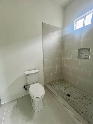 bathroom with tile patterned floors, a tile shower, and toilet