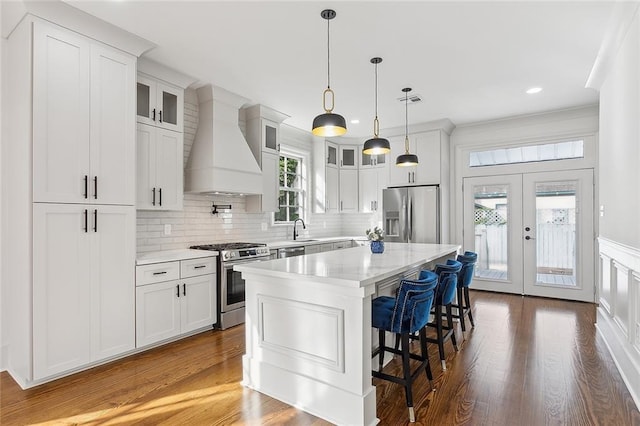 kitchen featuring white cabinetry, stainless steel appliances, a kitchen island, and custom exhaust hood