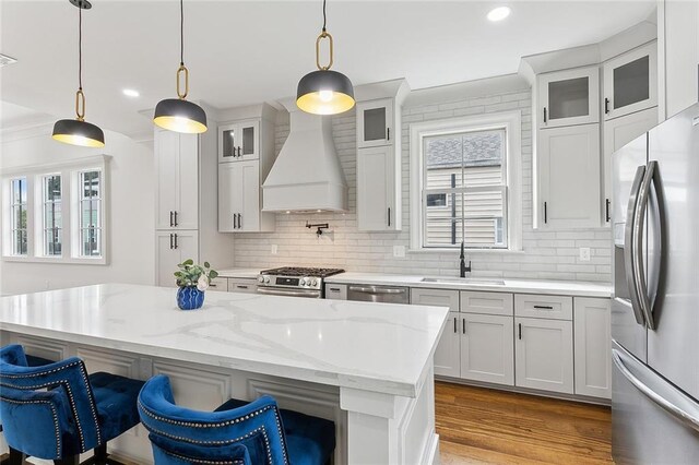 kitchen featuring pendant lighting, sink, appliances with stainless steel finishes, custom range hood, and white cabinets