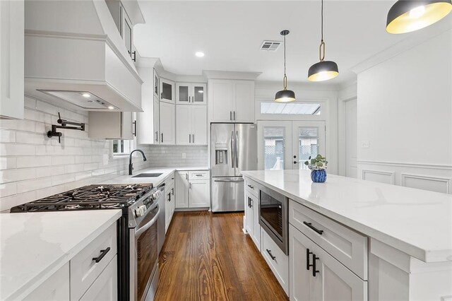 kitchen with hanging light fixtures, stainless steel appliances, white cabinetry, and light stone counters