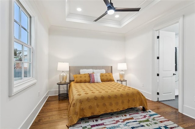 bedroom with ceiling fan, ornamental molding, hardwood / wood-style floors, and a tray ceiling