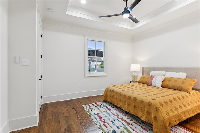 bedroom with a raised ceiling, ceiling fan, and dark hardwood / wood-style flooring