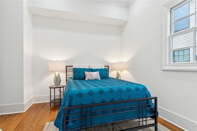 bedroom with multiple windows and hardwood / wood-style flooring