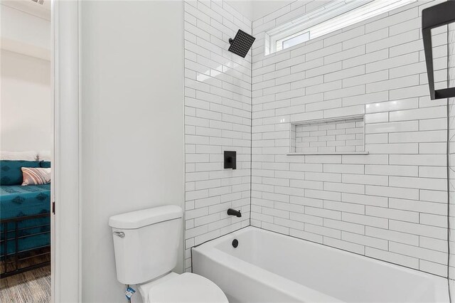 bathroom featuring hardwood / wood-style flooring, toilet, and tiled shower / bath