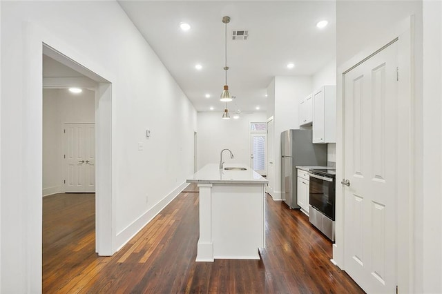 kitchen featuring appliances with stainless steel finishes, dark hardwood / wood-style flooring, decorative light fixtures, white cabinetry, and an island with sink