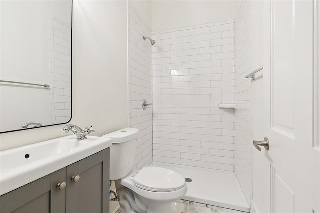 bathroom with a tile shower, vanity, and toilet