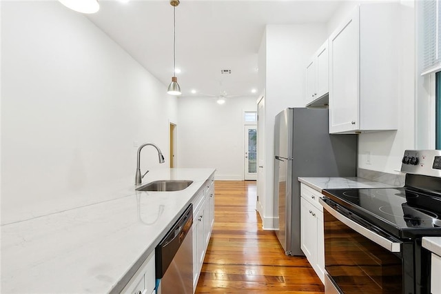 kitchen with sink, stainless steel appliances, light hardwood / wood-style flooring, decorative light fixtures, and white cabinets