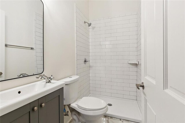 bathroom featuring tiled shower, vanity, and toilet