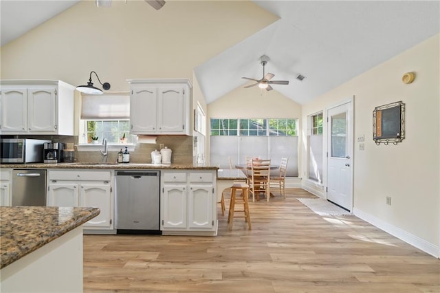 kitchen featuring white cabinets, appliances with stainless steel finishes, light hardwood / wood-style floors, and stone counters